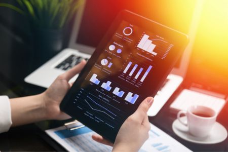 Hands holding ipad displaying charts and graphs